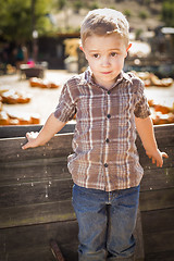 Image showing Little Boy Standing Against Old Wood Wagon at Pumpkin Patch
