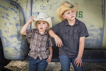 Image showing Two Young Boys Wearing Cowboy Hats Leaning Against Antique Truck