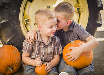 Image showing Two Boys Sitting Against Tractor Tire Holding Pumpkins Whisperin