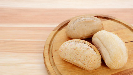 Image showing Three crusty petit pain on a bread board