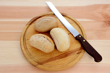 Image showing Three fresh rolls with a bread knife