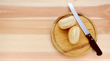 Image showing Two bread rolls, a knife and wooden cutting board