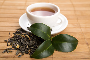 Image showing A cup of green tea with freh leaves