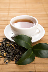 Image showing A cup of green tea with freh leaves