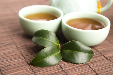 Image showing A cup of green tea with freh leaves