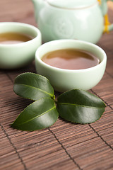 Image showing A cup of green tea with freh leaves