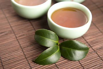 Image showing A cup of green tea with freh leaves