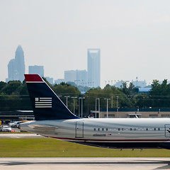 Image showing Commercial jet on an airport runway with city skyline in the bac