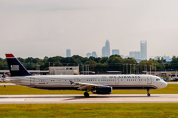 Image showing Commercial jet on an airport runway with city skyline in the bac