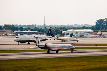 Image showing Commercial jet on an airport runway with city skyline in the bac