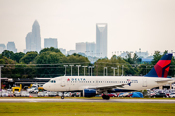 Image showing Commercial jet on an airport runway with city skyline in the bac