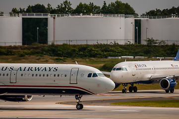 Image showing Commercial jet on an airport runway with fuel tanks in back