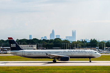 Image showing Commercial jet on an airport runway with city skyline in the bac