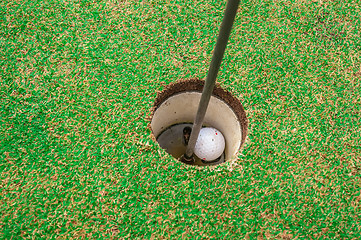 Image showing Golf ball on a green, in front of the hole,