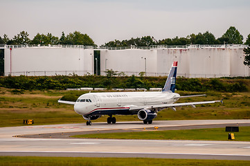 Image showing Commercial jet on an airport runway with fuel tanks in back