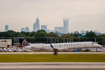 Image showing Commercial jet on an airport runway with city skyline in the bac