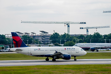 Image showing Commercial jet on an airport runway with city skyline in the bac