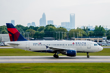 Image showing Commercial jet on an airport runway with city skyline in the bac