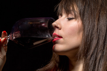 Image showing Young woman drinking red wine from a glass