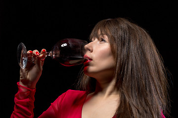 Image showing Young woman drinking red wine from a glass