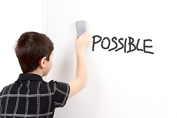 Image showing happy little boy erasing text on white board