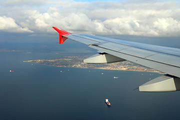 Image showing cargo ships under wing of flying plane