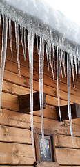 Image showing Wooden house with big icicles on snow-covered roof