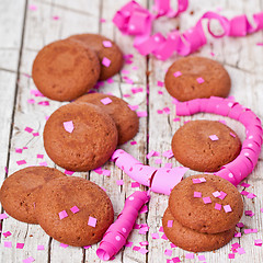 Image showing fresh chocolate cookies, pink ribbons and confetti 