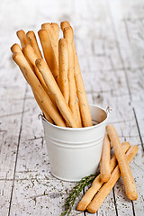 Image showing white bucket with bread sticks grissini and rosemary 