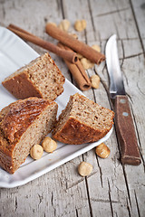 Image showing sliced fresh buns, old knife,hazelnuts and cinnamon