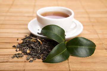 Image showing A cup of green tea with freh leaves