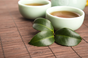 Image showing A cup of green tea with freh leaves