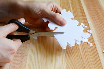 Image showing Using scissors to cut out a paper snowflake shape