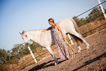 Image showing young woman walking a road with horse