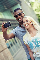 Image showing young smiling multiracial couple taking foto by smartphone 