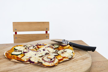 Image showing pizza with cutter on small desk