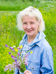 Image showing Portrait of a middle-aged woman with a bouquet of wild flowers