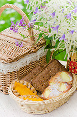 Image showing Buns in a wicker basket and a bouquet of field flowers  
