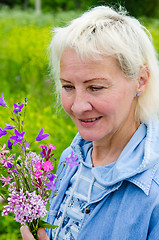 Image showing Portrait of a middle-aged woman with a bouquet of wild flowers