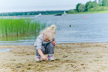 Image showing  Boy and girl playing in the sand on the shore of Lake 