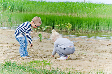 Image showing  Boy and girl playing in the sand on the shore of Lake 