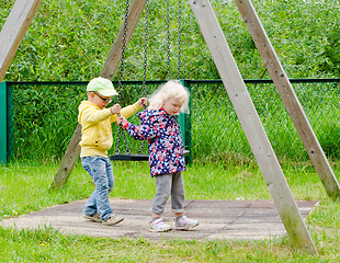 Image showing Young children, a boy with a girl swinging on a swing