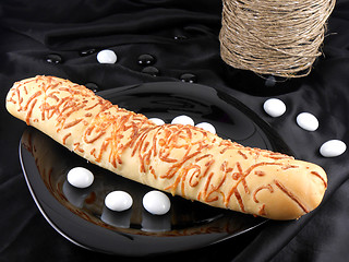 Image showing sweet cake on black background, white stones and wine bottle