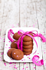 Image showing plate of fresh chocolate cookies with pink ribbon and confetti 