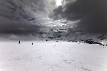 Image showing Ski slope, skiers and sky with storm clouds