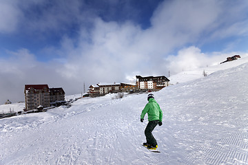 Image showing Hotels on ski resort and snowboarder on slope