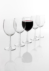 Image showing Glass filled with red wine in a row of empty glasses