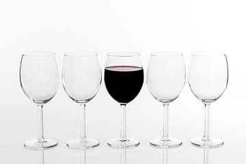 Image showing Glass of red wine in a row of empty glasses