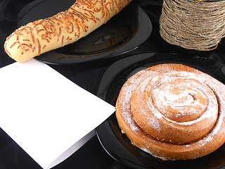 Image showing sweet cake on black background, white paper and wine bottle