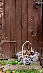 Image showing Basket of fir cones by a wooden door
